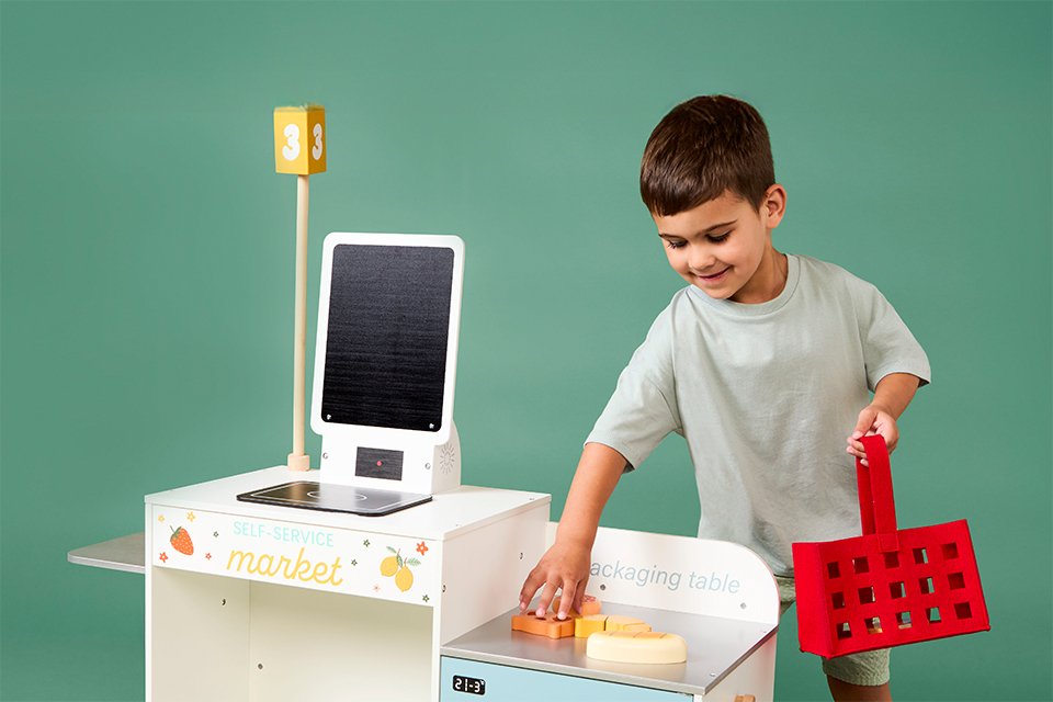 A boy smiling while using Chad Valley's kitchen toys to make breakfast.